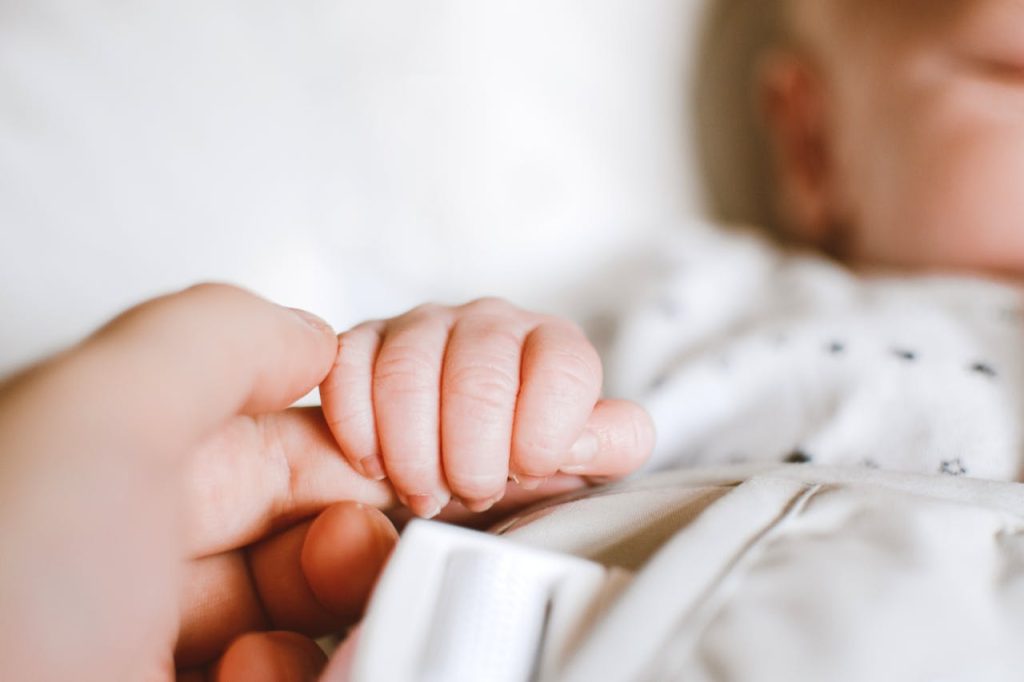 pexels photo 2721581 Close-up of a newborn's hand gently gripping a parent's finger, symbolizing love and connection.