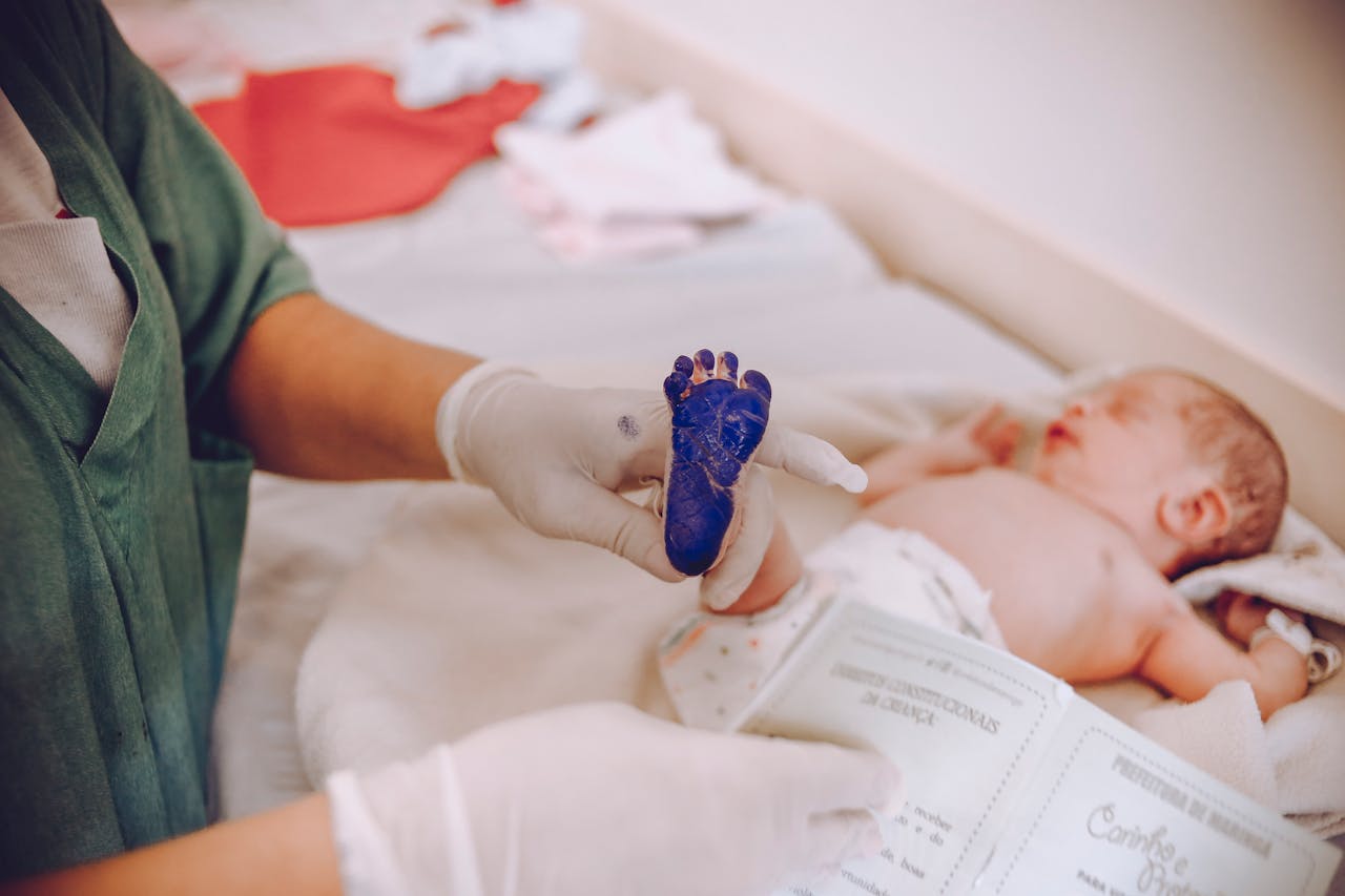 Services Medical professional taking footprint of a newborn baby in hospital setting.