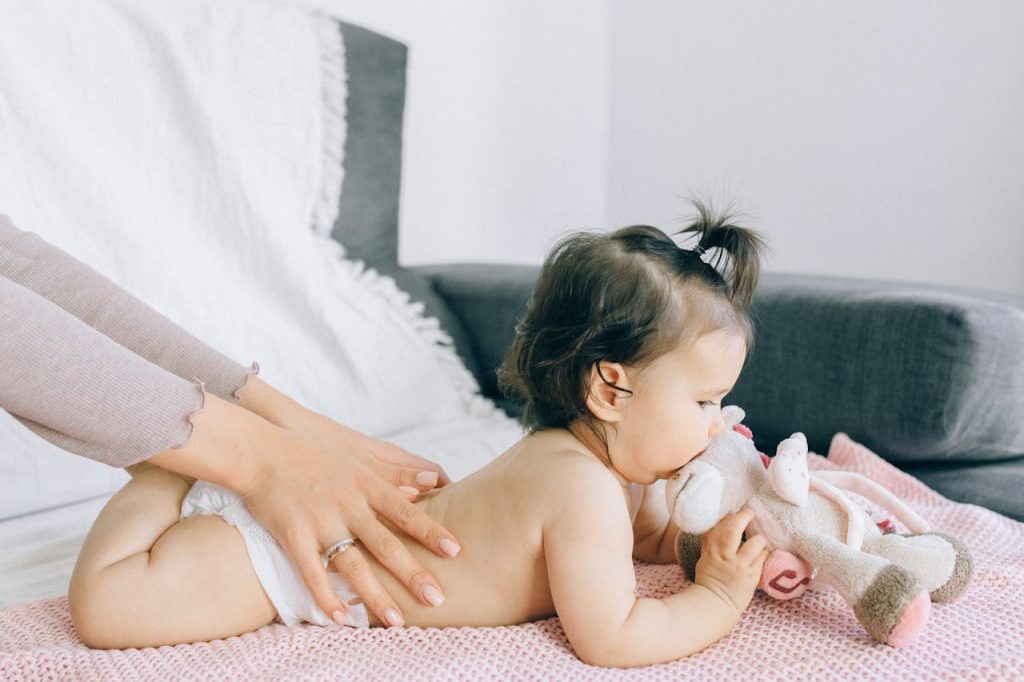 pexels photo 5889962 A serene moment of a baby receiving a gentle massage while holding a plush toy, epitomizing peace and comfort.